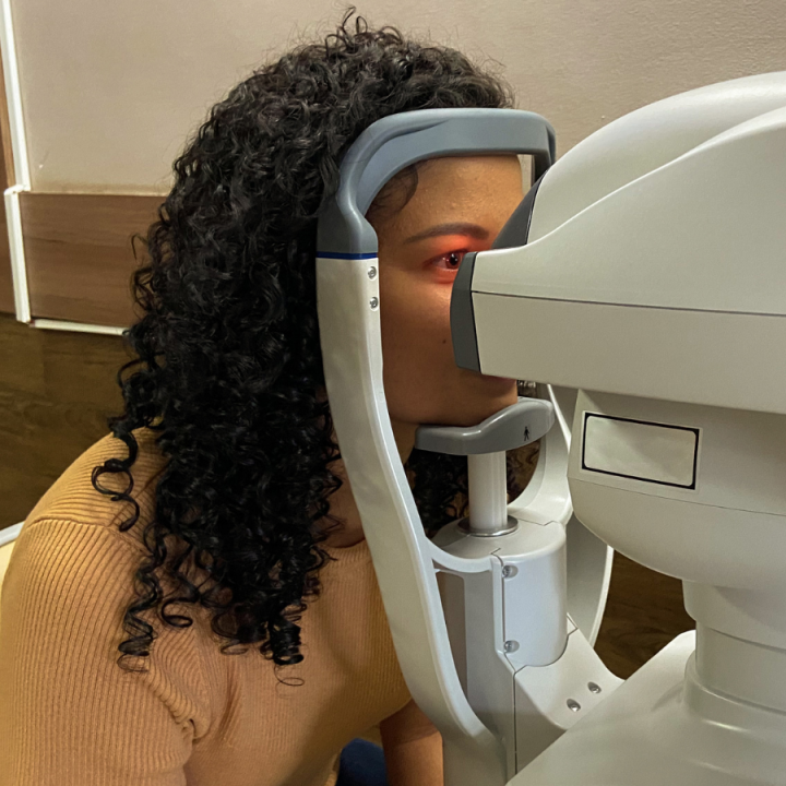 A Black woman gets her eyes examined by a machine