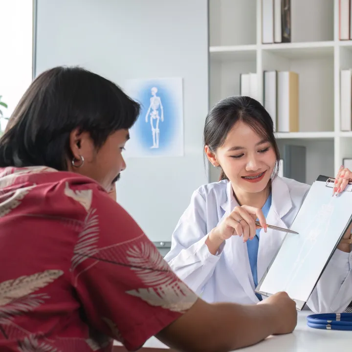 Female doctor explains a document to a smiling male patient in an office.
