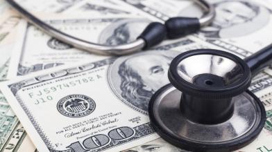 Stethoscope sitting on top of $100 bills