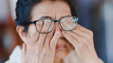 A woman rubs her eyes due to floaters in her vision from diabetes related eye disease