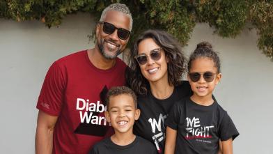 A family of four wearing black or red shirts promoting diabetes awareness, posing for a picture.