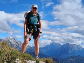A woman standing on a mountain peak with a backpack.