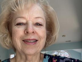 a woman with blond hair smiles at the camera