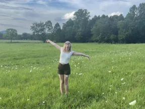Woman with her arms spread out standing in a field