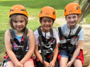 Three smiling girls in orange helmets and harnesses at an ADA diabetes day camp.