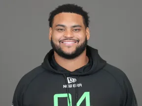 Smiling man with a beard and dark hair, wearing a black hoodie.