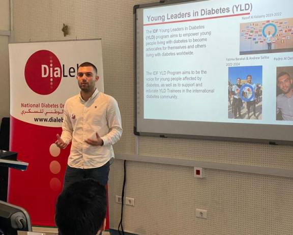 A man presenting in front of a screen about young leaders in diabetes.