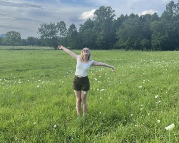 Woman with her arms spread out standing in a field