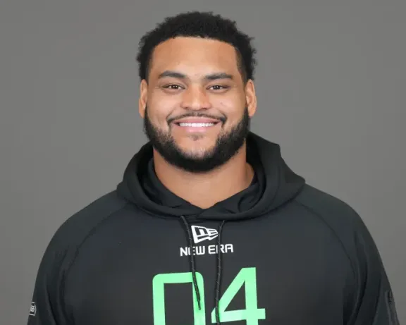 Smiling man with a beard and dark hair, wearing a black hoodie.