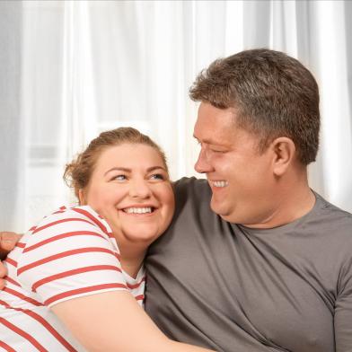 An overweight couple hug each other while smiling