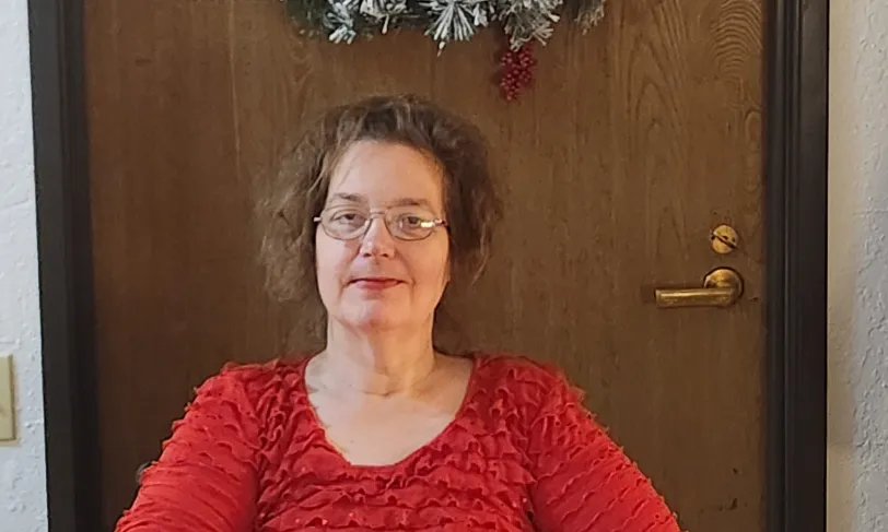 Photo of Christine sitting front of a door with a wreath.