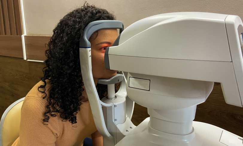 A Black woman gets her eyes examined by a machine