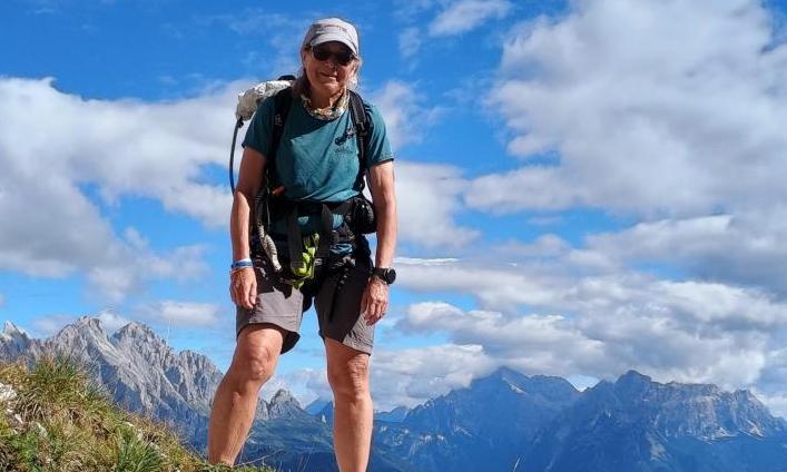 A woman standing on a mountain peak with a backpack.