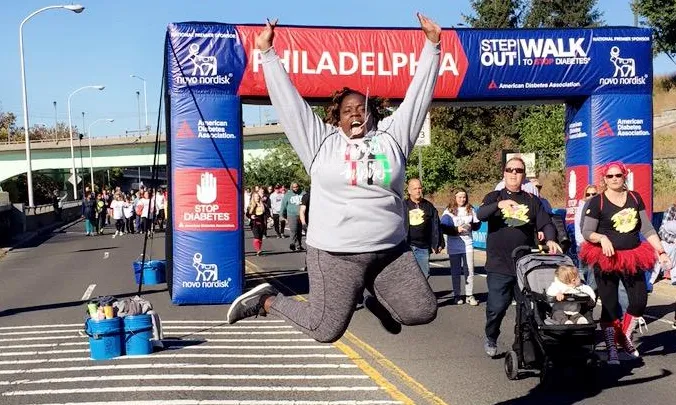 Person jumps in front of the Step Out Walk for Diabetes banner.