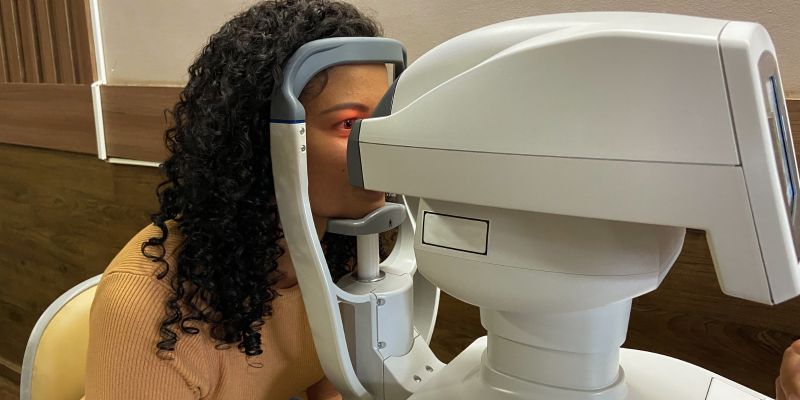 A Black woman gets her eyes examined by a machine