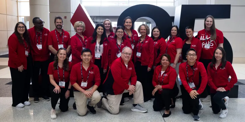 ADA staff volunteer red shirts stands before large ADA branding at Scientific Sessions..