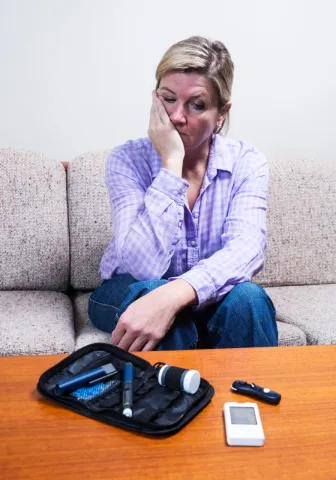 A woman looks sadly at her blood glucose monitor.