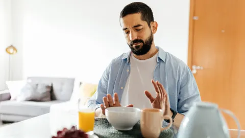 A man pushes away food because he is full. 