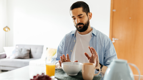 A man pushes away food because he is full. 