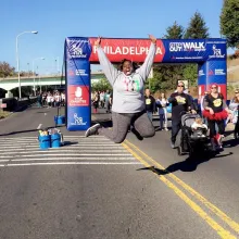 Person jumps in front of the Step Out Walk for Diabetes banner.