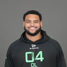 Smiling man with a beard and dark hair, wearing a black hoodie.