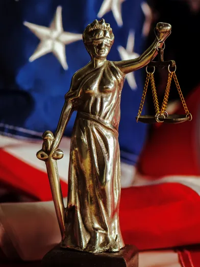 Scales of justice bronze statue over American flag