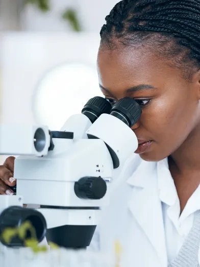 African American woman researcher looking in microscope
