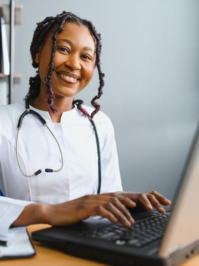 Smiling African American physician typing on laptop computer