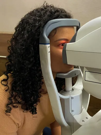A Black woman gets her eyes examined by a machine